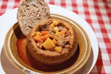 Goulash in a bread bowl in white plateの写真素材