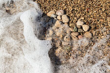 Heart shape created with sea pebbles on a sand and waves