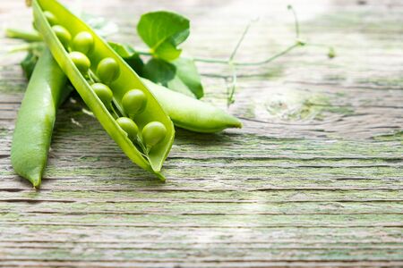 Green fresh ripe pea pod on a wooden desk outdoor in a gardenの写真素材