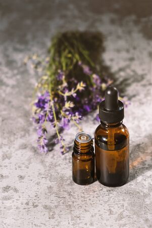 Lavender essential oil in a brown glass bottle with a lavender flowers on background.の写真素材