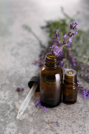 Lavender essential oil in a brown glass bottle with a lavender flowers on background.の写真素材
