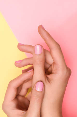 Female hands with pink nail design. Pink nail polish manicured hands. Female hands on yellow backgroundの写真素材
