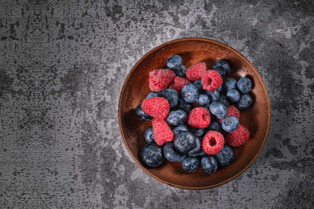 Blueberry and raspberry in a clay plate. Raw berries mix close upの写真素材