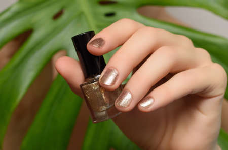 Female hand with golden nail design. Golden nail polish manicured hand. woman hand hold golden...