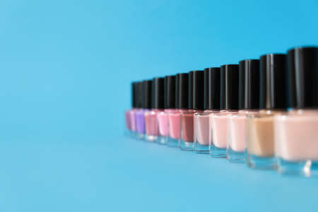 Group of bright nail polishes on blue background. Set of nail polish bottles