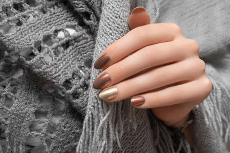 Female hands with gold nail design. Red nail polish manicured hands. Woman hands hold gray wool shawlの写真素材
