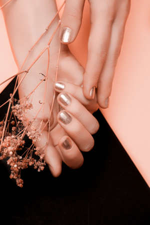 Female hand with golden nail design. Golden nail polish manicure. female holding yellow flowerの写真素材