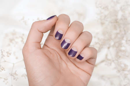 Female hand with Christmas nail design. Purple nail polish manicure. Female hand on a snowflake background.の写真素材