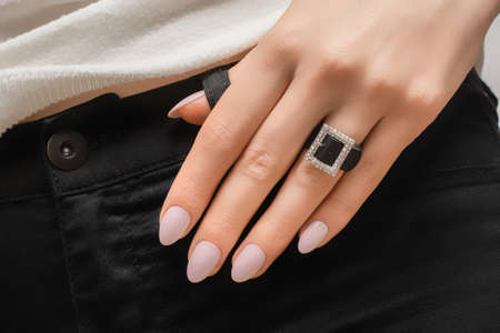 Female hand with pink nail design. Rose glitter nail polish manicure. Woman hand on a hip