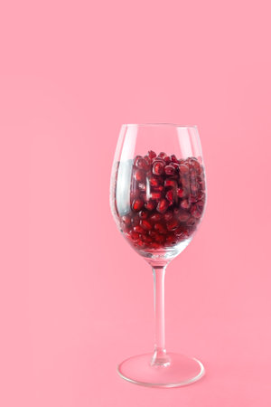 Close-up of pomegranate seeds in a wine glass on a pink background.の写真素材