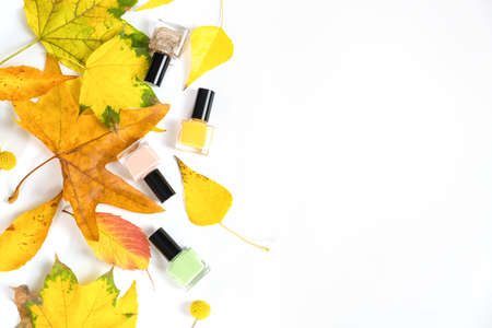 Nail polish bottles with yellow autumn leaves. Green, rose, yellow nail polish bottles.