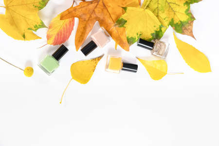 Nail polish bottles with yellow autumn leaves. Green, rose, yellow nail polish bottles. top view copyspace.の写真素材