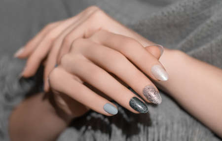 Female hands with glitter silver nail design. Silver nail polish manicure. Woman hands hold gray wool shawl.の写真素材