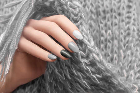 Female hand with silver nail design. Glitter black nail polish manicure. Woman hand hold gray wool shawlの写真素材