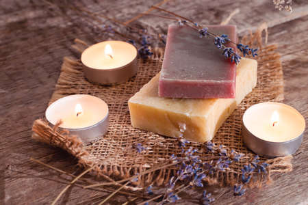 Red and yellow soaps with a scented candle in a romantic setting. Spa concept on wooden background. wellness concept.の写真素材