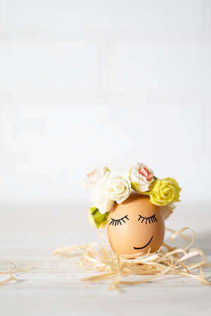 Easter egg with funny faces. Funny easter egg decorated yellow roses wreath