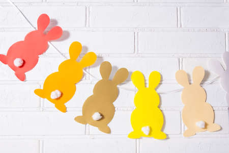Paper Easter bunnies garland. Easter rabbits garland on a stone brick wall