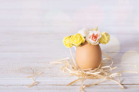 Easter egg on a white desk. Funny easter egg decorated yellow roses wreath