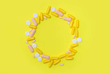 Yellow and white pharmaceutical medicine capsules over yellow background.の写真素材