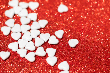 Valentine's day candies on red glitter background. Valentine's day white heart shaped candiesの写真素材