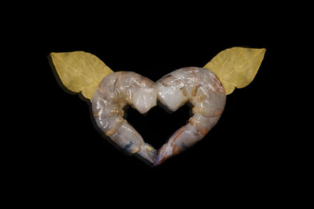 Raw king shrimps form love symbol on black background. King shrimps shape heart symbol. St. Valentine's day.の写真素材