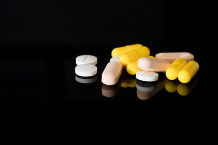 Yellow pharmaceutical medicine capsules over black background. copy spaceの写真素材
