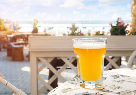 Pint of cold beer on the table in cafe, blurry backgroundの写真素材