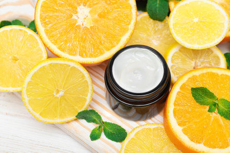 Jar of white body cream citrus cream on a background of oranges. Natural citrus face cream for anti-aging effectの写真素材