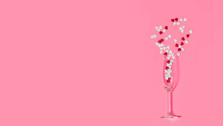 Heart shaped candies in glass top view. Valentine's day candies in champagne glass. Heart shaped candies on pink background. copy space.の写真素材