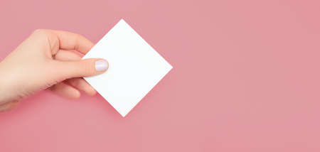 Hand of women holding blank paper label, isolated on pink background. copy spaceの写真素材