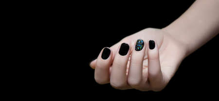 Beautiful female hand with black nail design isolated on dark backgroundの写真素材