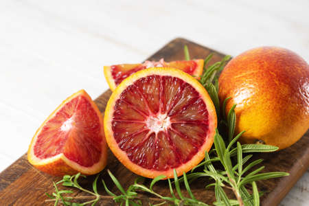 Ripe red oranges on wooden cut board. Sliced and whole ripe juicy Sicilian Blood oranges on wooden backgroundの写真素材