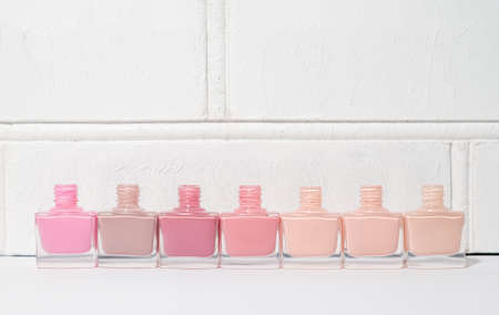 Set of open nail polish bottles without brushes. Group of nail polish on white wall background. copy spaceの写真素材