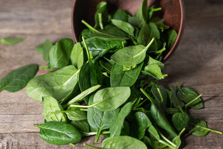 Fresh spinach leaves in a bowl on rustic wooden table. Vegetarian meal. Raw spinach in a bowl