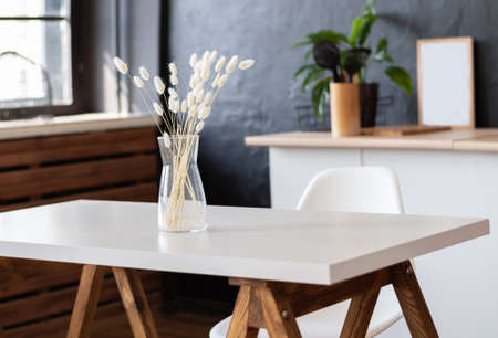Dried flowers in the glass jar on a white table. Clean kitchen with a white dry flowers in a vase on a tableの写真素材
