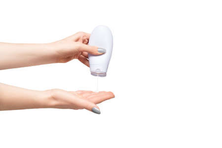 Woman pouring body care lotion on her hand isolated on white background. female hold skincare cream tubeの写真素材