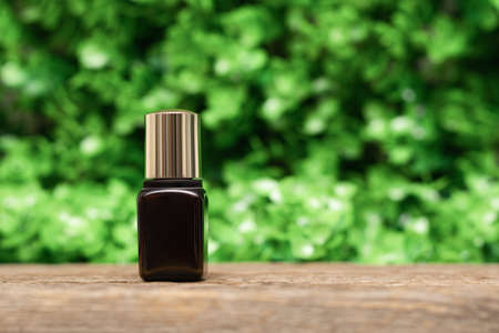 Essential oil bottle in spring garden. Essential oil brown bottle on wooden desk on green leaves background. copy space.の写真素材