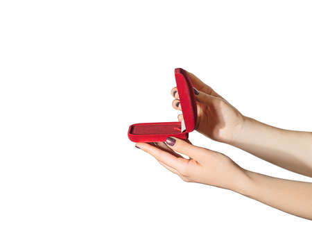 Female hands with purple nail design. Glitter purple nail polish manicure. Woman hands hold red present box on a white backgroundの写真素材