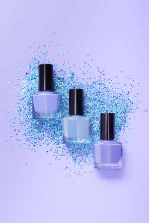 Several blue nail polish bottles on purple background. Set of purple nail polish bottles with glitter blue decoration.の写真素材