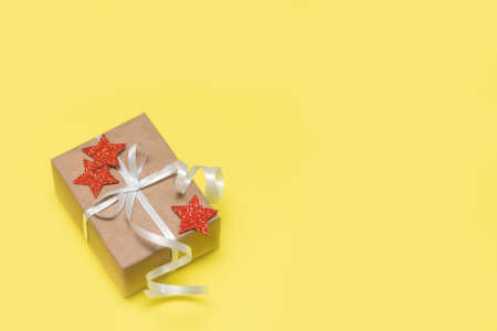 Gift box on yellow background. Holiday greeting card. Paper gift box with red stars on yellow background. copy spaceの写真素材