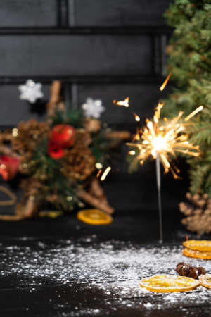 Christmas sparkler with dried fruits on decorated pine tree background.