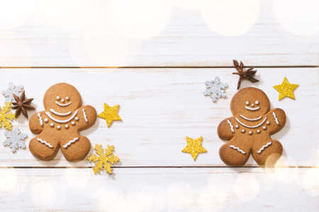 Christmas gingerbread men, golden sparkling stars and star anise on a white wooden background. Merry Christmas greeting card. copy space.の写真素材