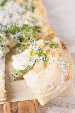 Roman pizza with cheese cut in pieces and served on a wooden board. Traditional roman cheese pizza on white wooden background.の写真素材