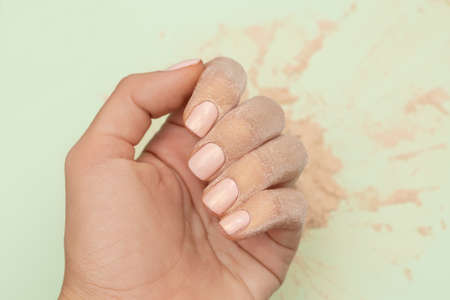 Female hand with pink nail design. Pink nail polish manicure. Woman hand covered with gold face...