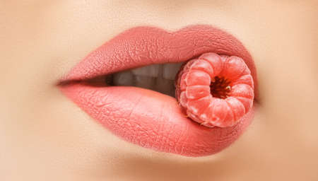 Perfect female lips. Close up female lips with raspberry. Raspberry color female lips with eating raspberry. Pink lips with raspberries.の写真素材