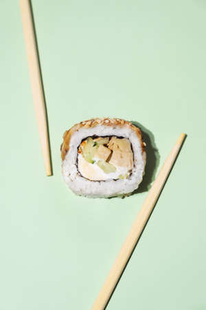 Fresh salmon sushi with wooden chopsticks on green background. Sushi roll with chopsticks. fish sushi rollの写真素材