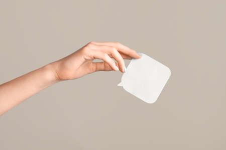 Female hand with gray manicure holding a white blank message card. Speech shape banner in female hand on beige background. copy space.の写真素材