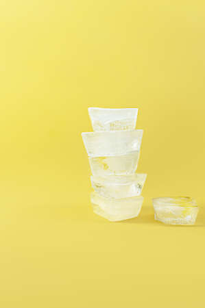 Ice cube tower on yellow background. Ice tower on yellow background. Ice cube stacksの写真素材