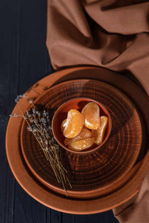 Tangerine slices on a brown clay plate with lavender flowers. Fresh mandarin slices on a dark backgroundの写真素材