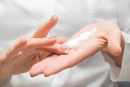 Female model hands with perfect manicure applying moisturizer cream. Female applying hands care lotion. Body care lotion on a female palmの写真素材